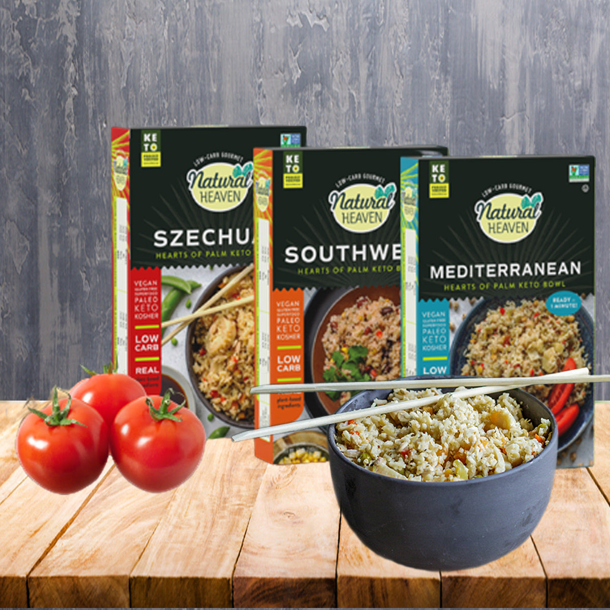 Three boxes of Natural Heaven Hearts of Palm Keto Bowls labeled Szechuan, Southwest, and Mediterranean are displayed on a wooden table, alongside a bowl of pasta and fresh red tomatoes.