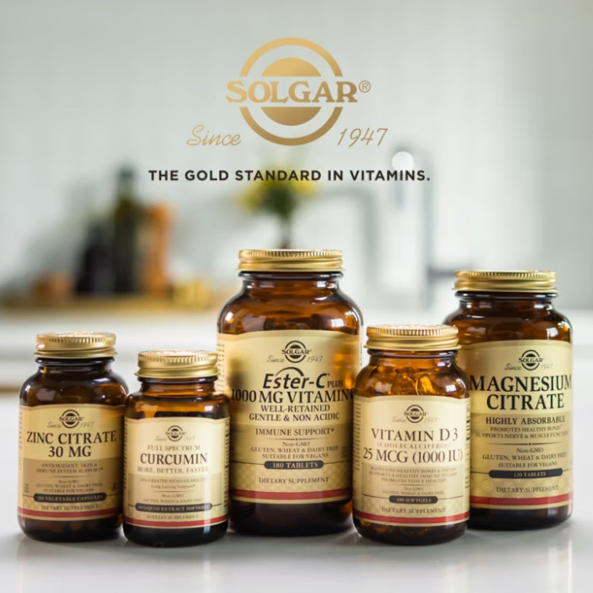 Five amber glass bottles of Solgar dietary supplements, including Ester-C, Vitamin D3, and Magnesium Citrate, are displayed on a kitchen countertop with a blurred background.