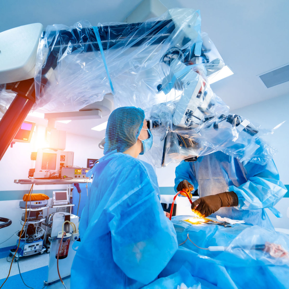 A surgeon in blue scrubs and gloves performs a bariatric surgery using a robotic surgical system, while an assistant observes in a bright, sterile operating room.