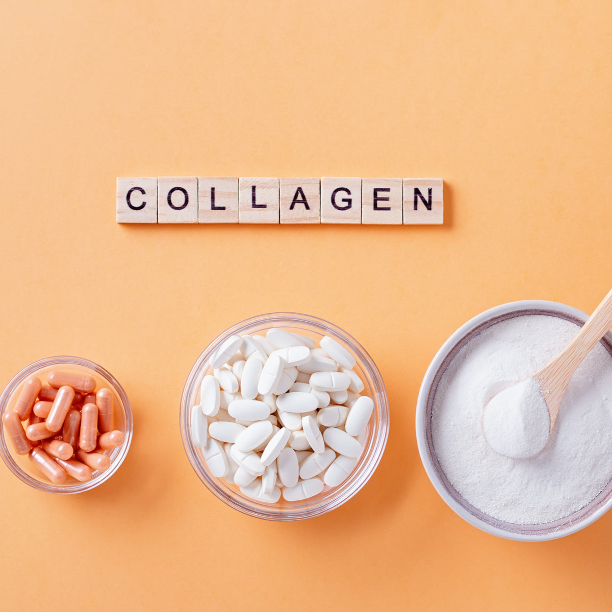 Three bowls contain different forms of collagen supplements: orange capsules, white tablets, and a bowl of powder with a wooden spoon, arranged above the word "COLLAGEN" spelled out in letter tiles on an orange background.