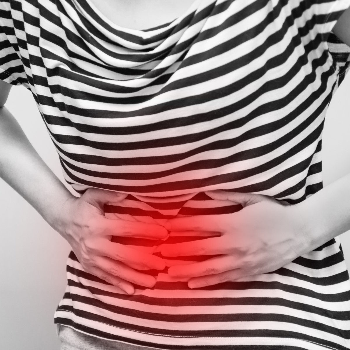 A person in a striped shirt is holding their stomach with both hands, showing signs of discomfort, with a red overlay indicating pain, suggesting a discussion about dumping syndrome.