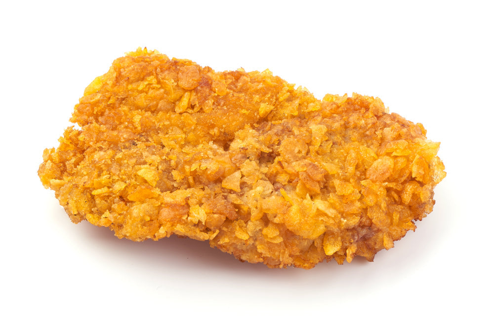 A crispy, golden-brown mock fried chicken piece, coated in crunchy cornflakes, is displayed on a white background, highlighting its texture and appetizing appearance.