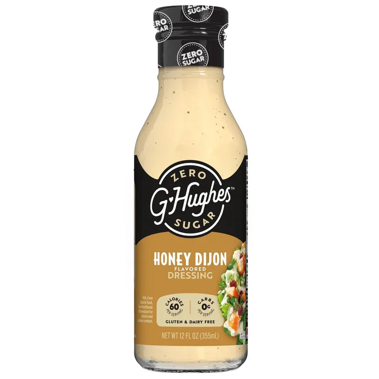 A clear bottle of G. Hughes Honey Dijon flavored dressing, labeled as zero sugar, gluten-free, and dairy-free, features a salad image on the front and displays nutritional information on the side.