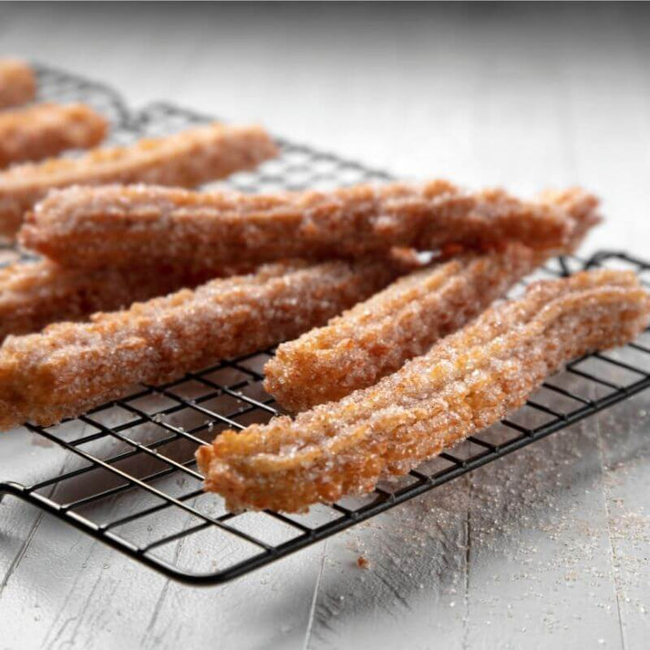 Golden-brown churros coated in sugar, arranged on a black wire rack, showcasing their crispy texture and elongated shape.