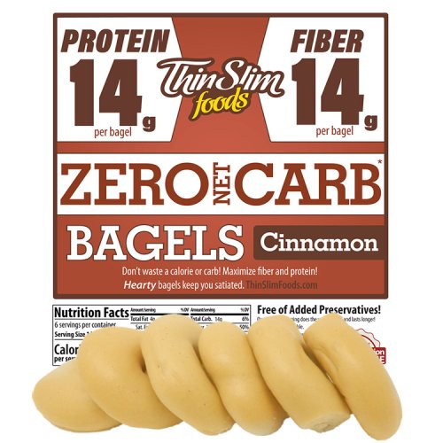 Cinnamon bagels are displayed in front of a product package highlighting "Zero Net Carb" with nutritional information, emphasizing 14g of protein and fiber per bagel.