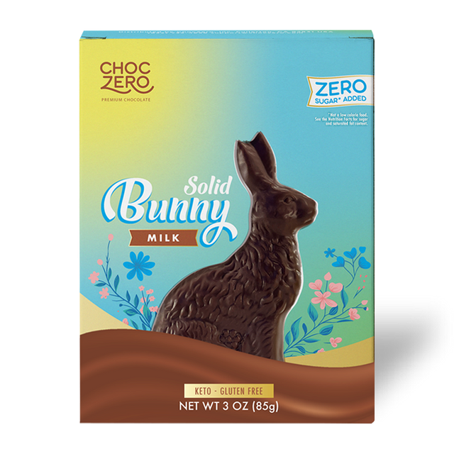 A solid chocolate bunny is prominently displayed on a colorful packaging featuring flowers, with labels indicating it is milk chocolate, keto-friendly, gluten-free, and contains zero sugar.