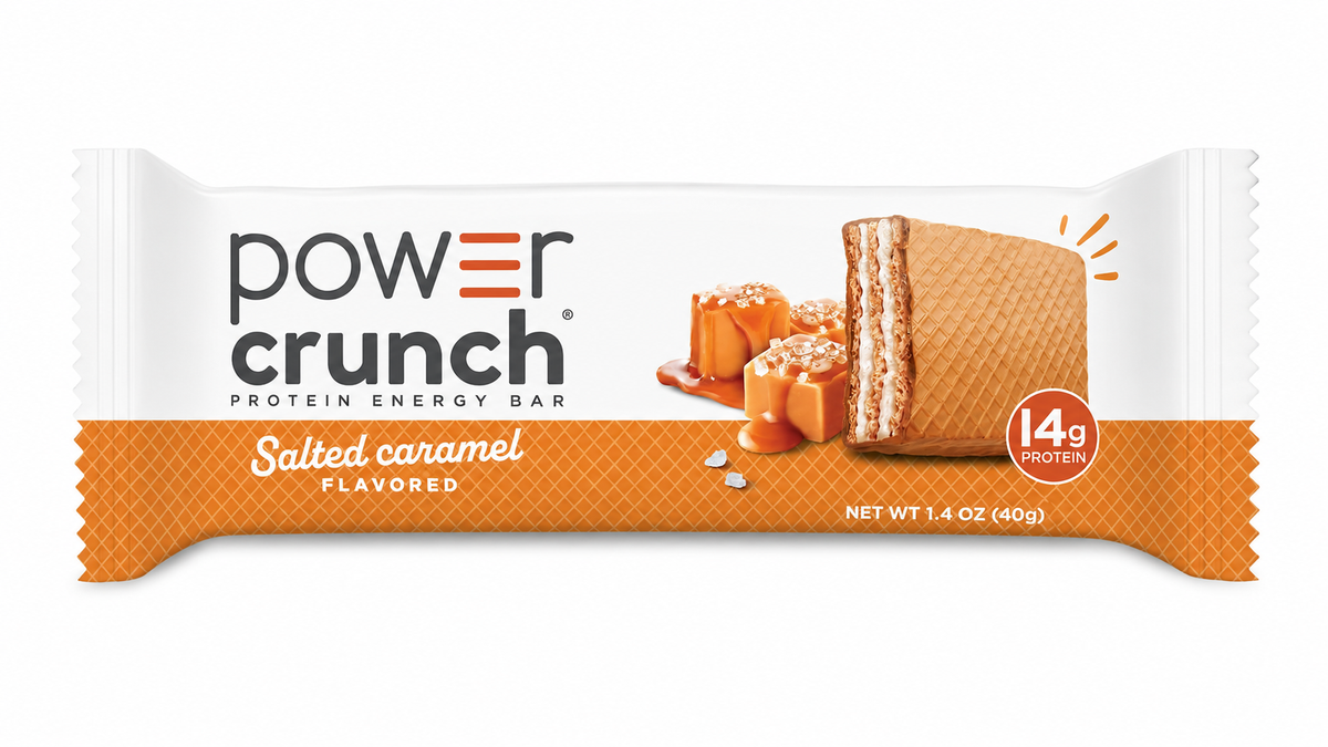 A protein energy bar packaging features a salted caramel flavor, displaying a bar with a crispy texture and caramel pieces, highlighted with an orange and white design.