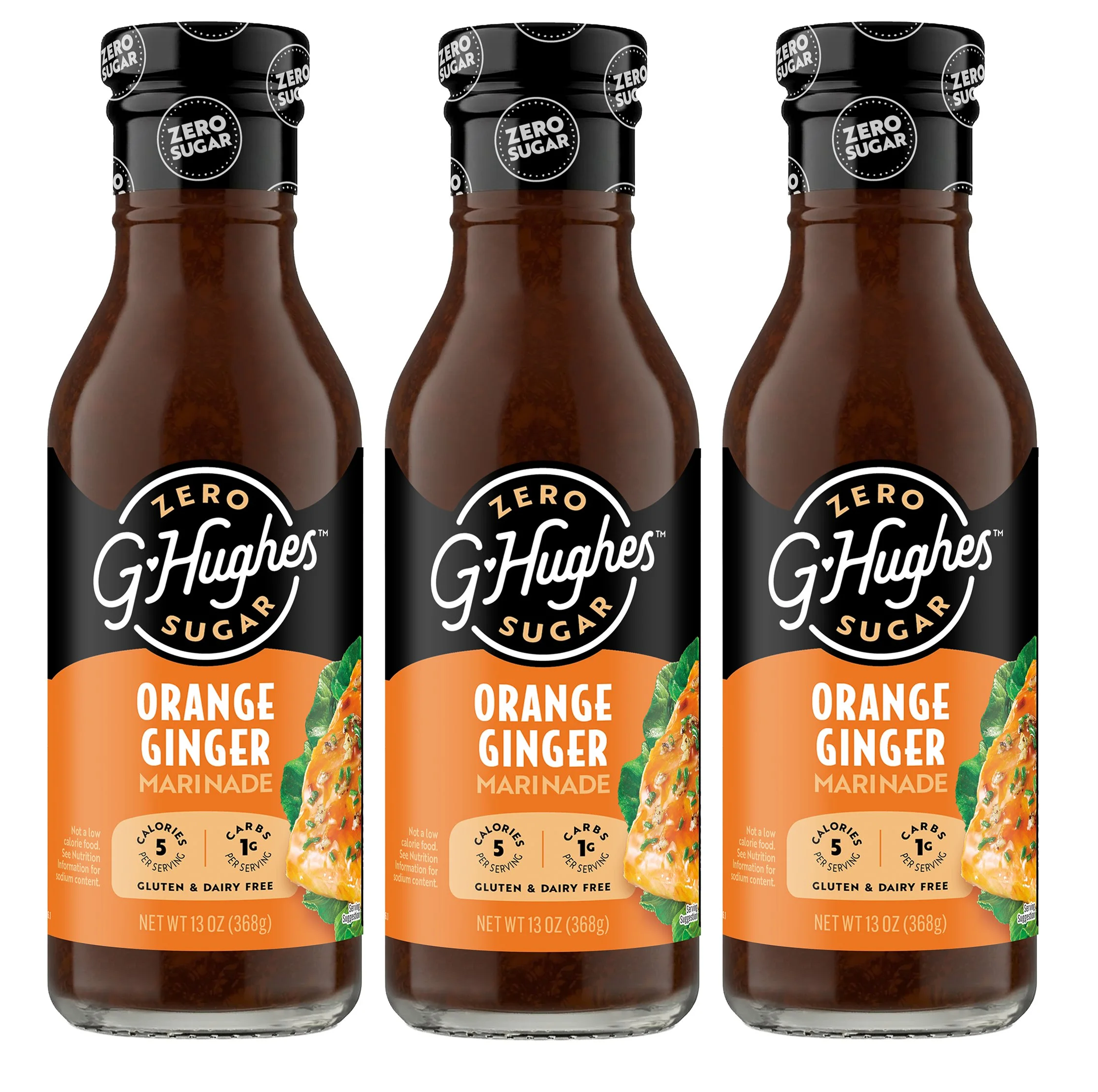 Three bottles of G. Hughes Orange Ginger Marinade are displayed, featuring a black label with orange accents, highlighting that the product is zero sugar, gluten-free, and dairy-free.