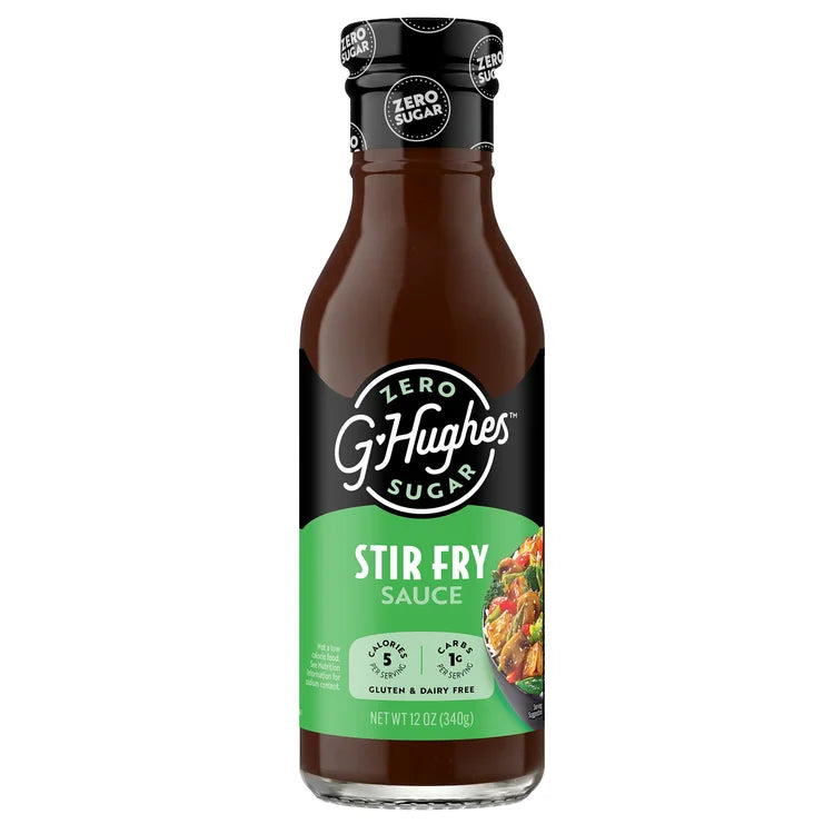 A bottle of G. Hughes Zero Sugar Stir Fry Sauce features a dark brown liquid, a black cap, and a green label highlighting its low-calorie, gluten-free, and dairy-free attributes.