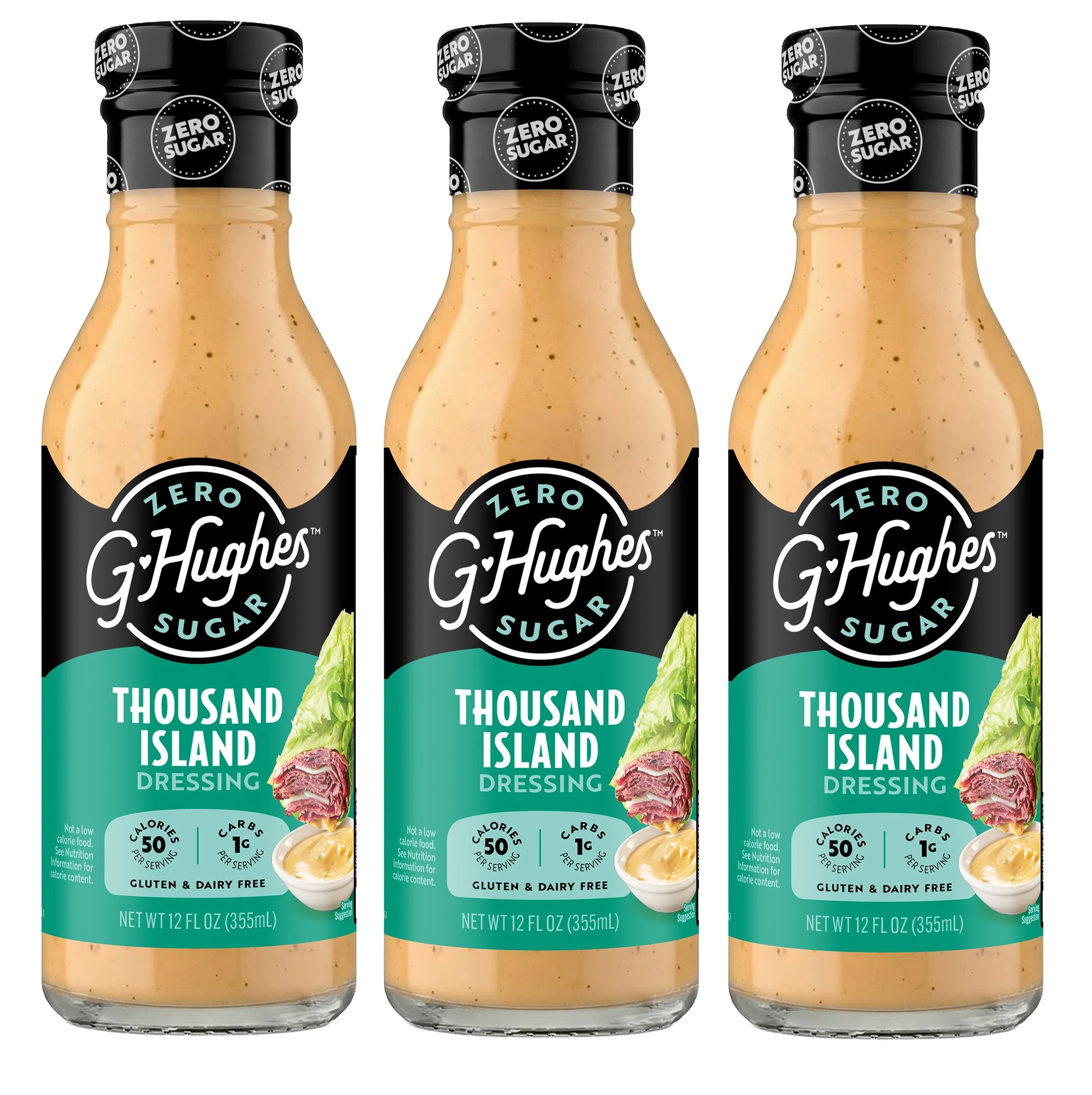 Three bottles of G. Hughes Zero Sugar Thousand Island Dressing are displayed, featuring a creamy orange color, a black and teal label, and images of lettuce and meat on the front, emphasizing its low-calorie content.