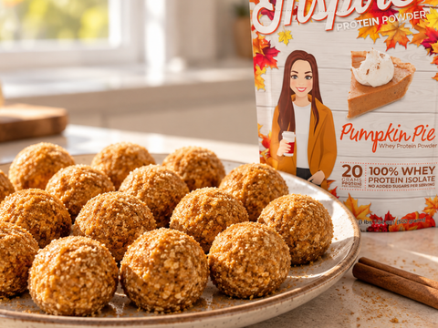 No-bake pumpkin protein balls coated in golden sugar crystals on a speckled ceramic plate, featuring Inspire Pumpkin Pie Whey Protein Powder, with cinnamon sticks and cozy fall decor in a sunlit kitchen.