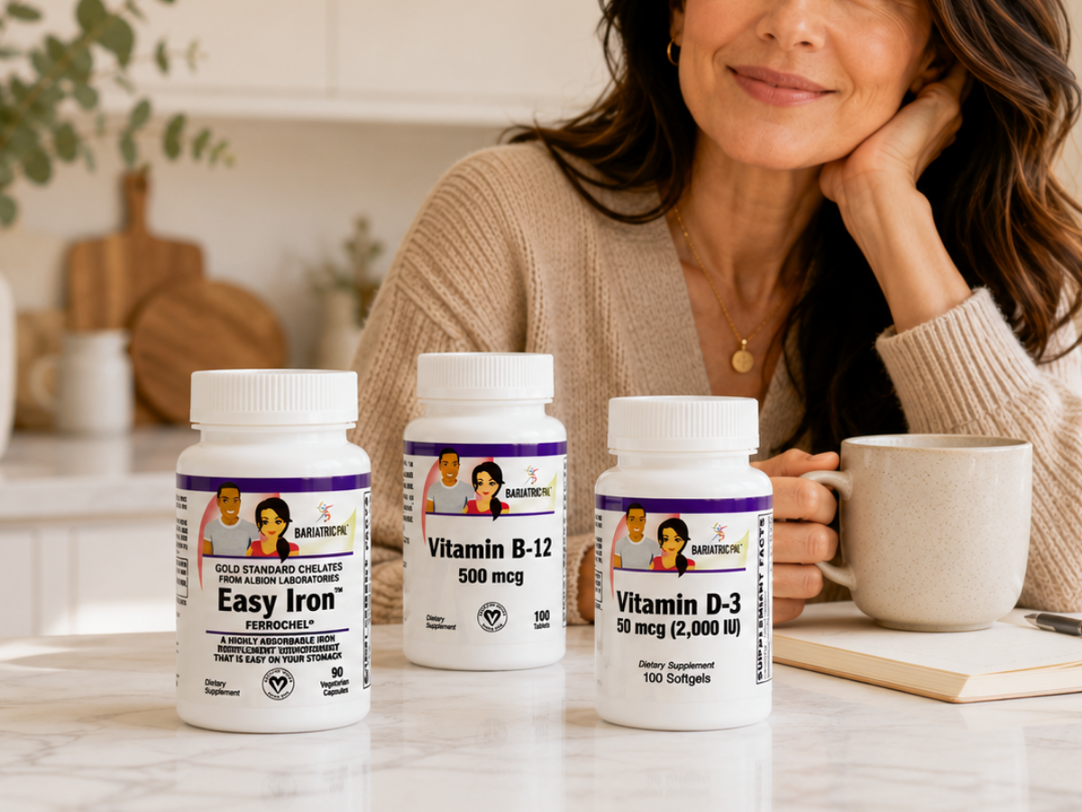 A woman with long, wavy hair smiles while holding a mug, sitting at a table with three vitamin bottles labeled Easy Iron, Vitamin B-12, and Vitamin D-3, surrounded by a cozy kitchen setting.