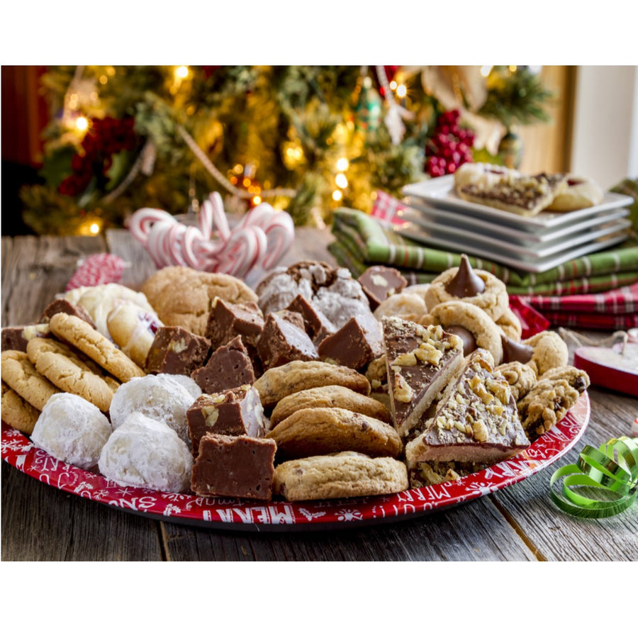 A festive platter filled with various bariatric-friendly desserts, including cookies and fudge, is displayed on a rustic wooden table, with a decorated Christmas tree and holiday decorations in the background.