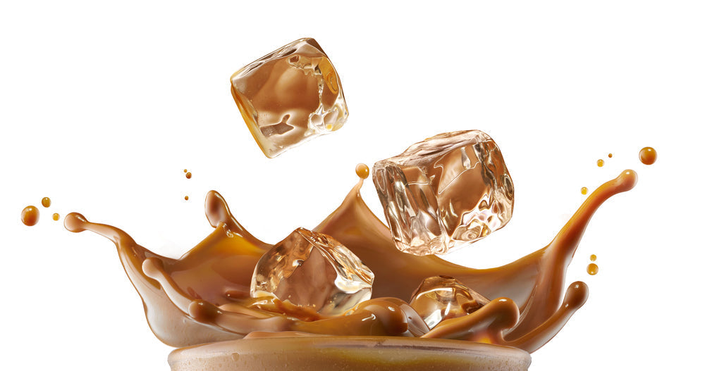 A glass filled with cola splashes as ice cubes fall into it, creating a dynamic scene with droplets flying in a bright, white background.