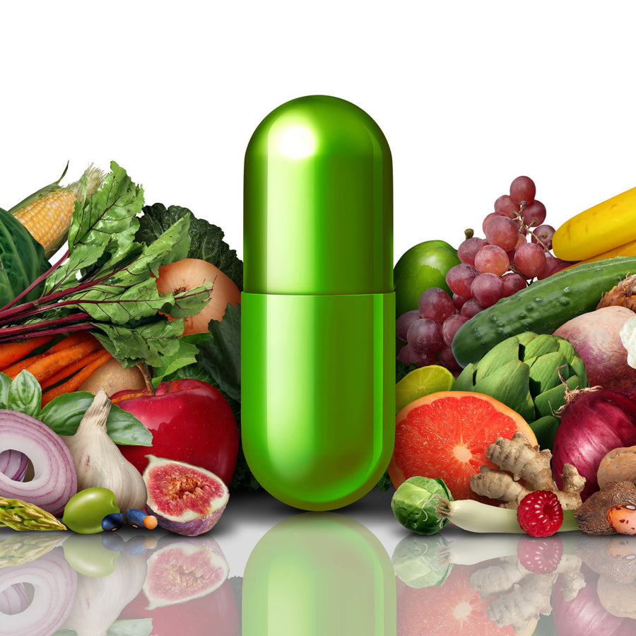 A large green capsule stands prominently in front of a colorful assortment of fresh fruits and vegetables, highlighting the importance of vitamins and minerals after bariatric surgery.