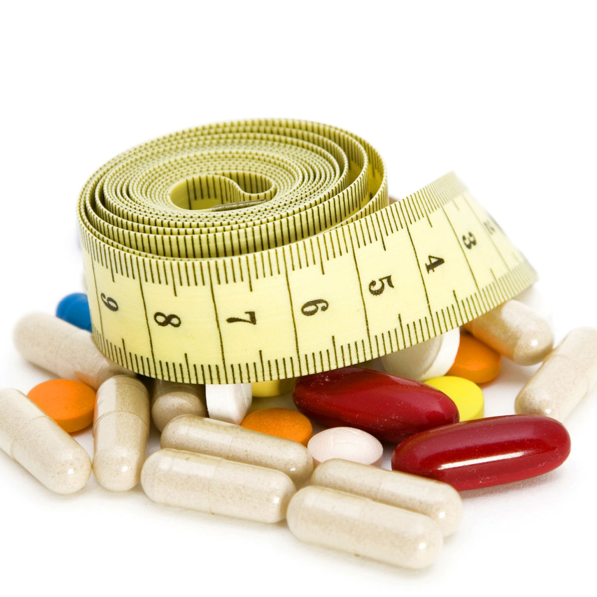 A yellow measuring tape is coiled on top of a variety of colorful vitamins and supplements, symbolizing the connection between nutrition and weight loss.