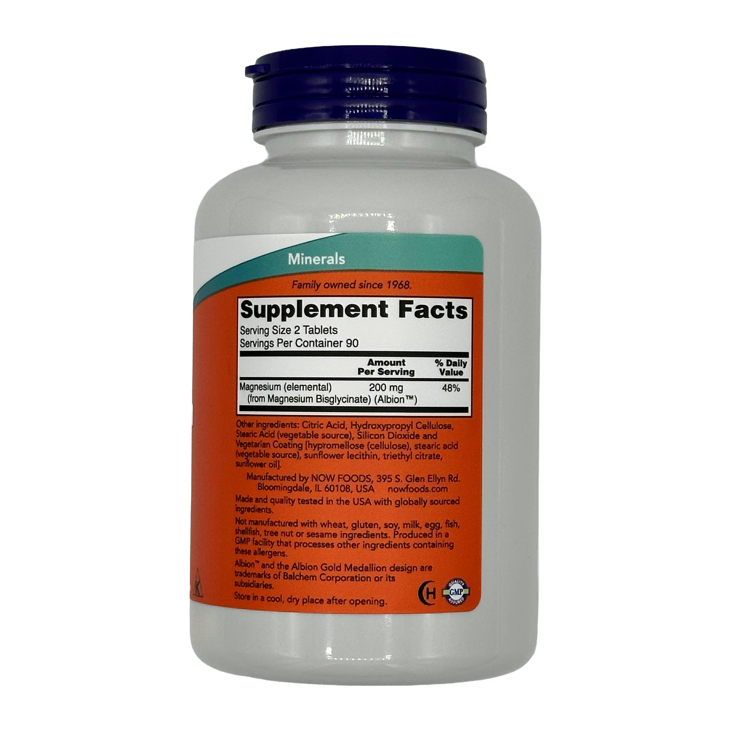 A white bottle with a blue cap displays the supplement facts for magnesium tablets, including serving size, amount per serving, and ingredients, set against a plain black background.