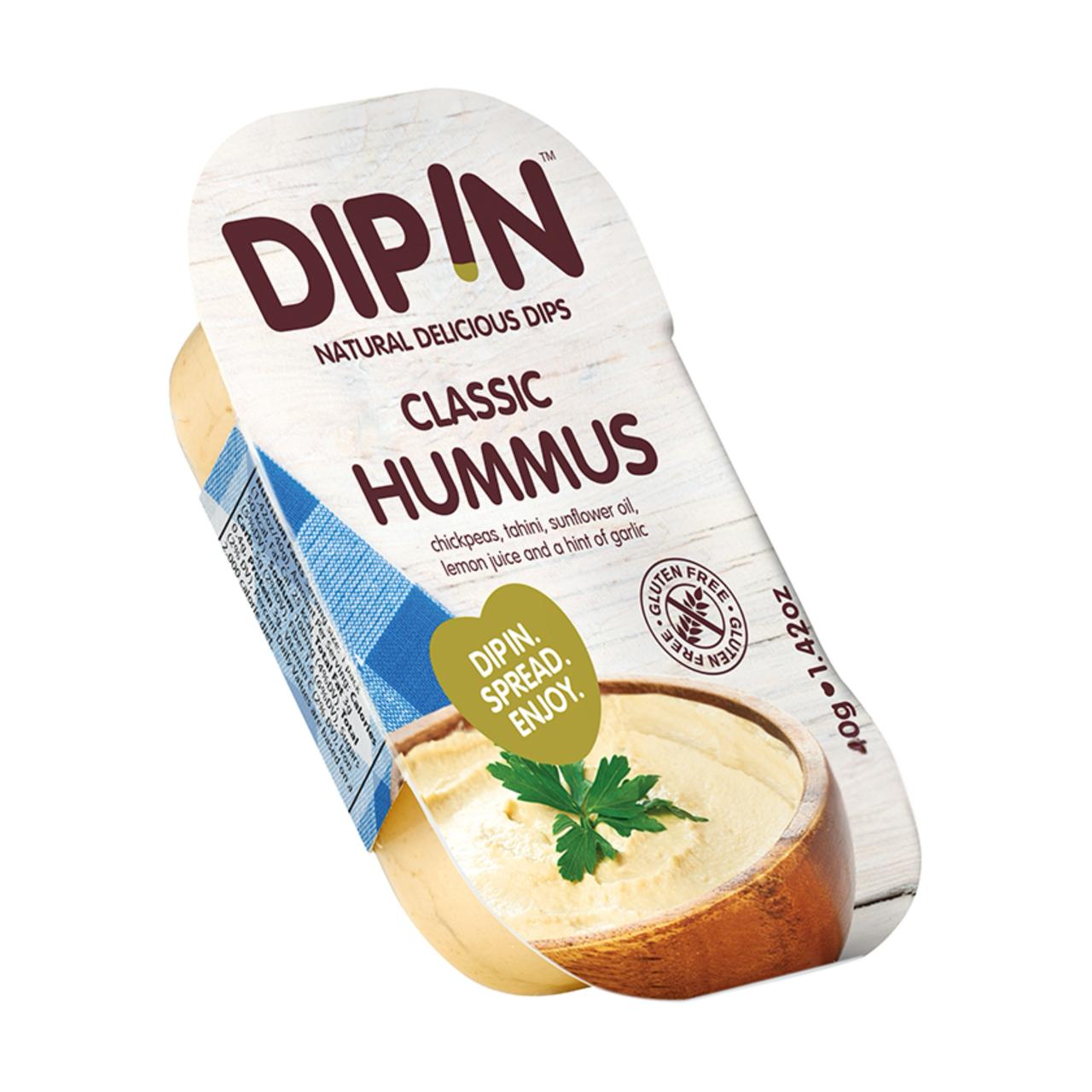A container of DIP IN classic hummus, featuring a creamy texture topped with a sprig of parsley, is displayed against a light wooden background, highlighting its gluten-free ingredients.