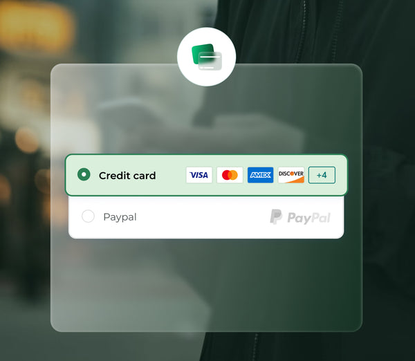 A person holds a smartphone in a blurred outdoor setting, displaying a payment interface with options for credit card and PayPal, featuring various card logos.