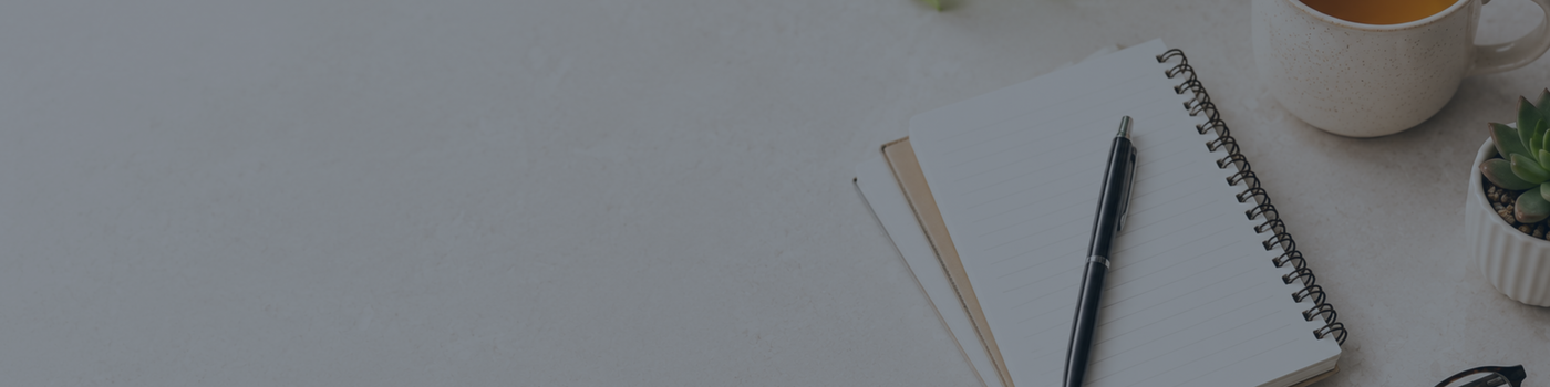 Notebook, pen, and mug on a white surface