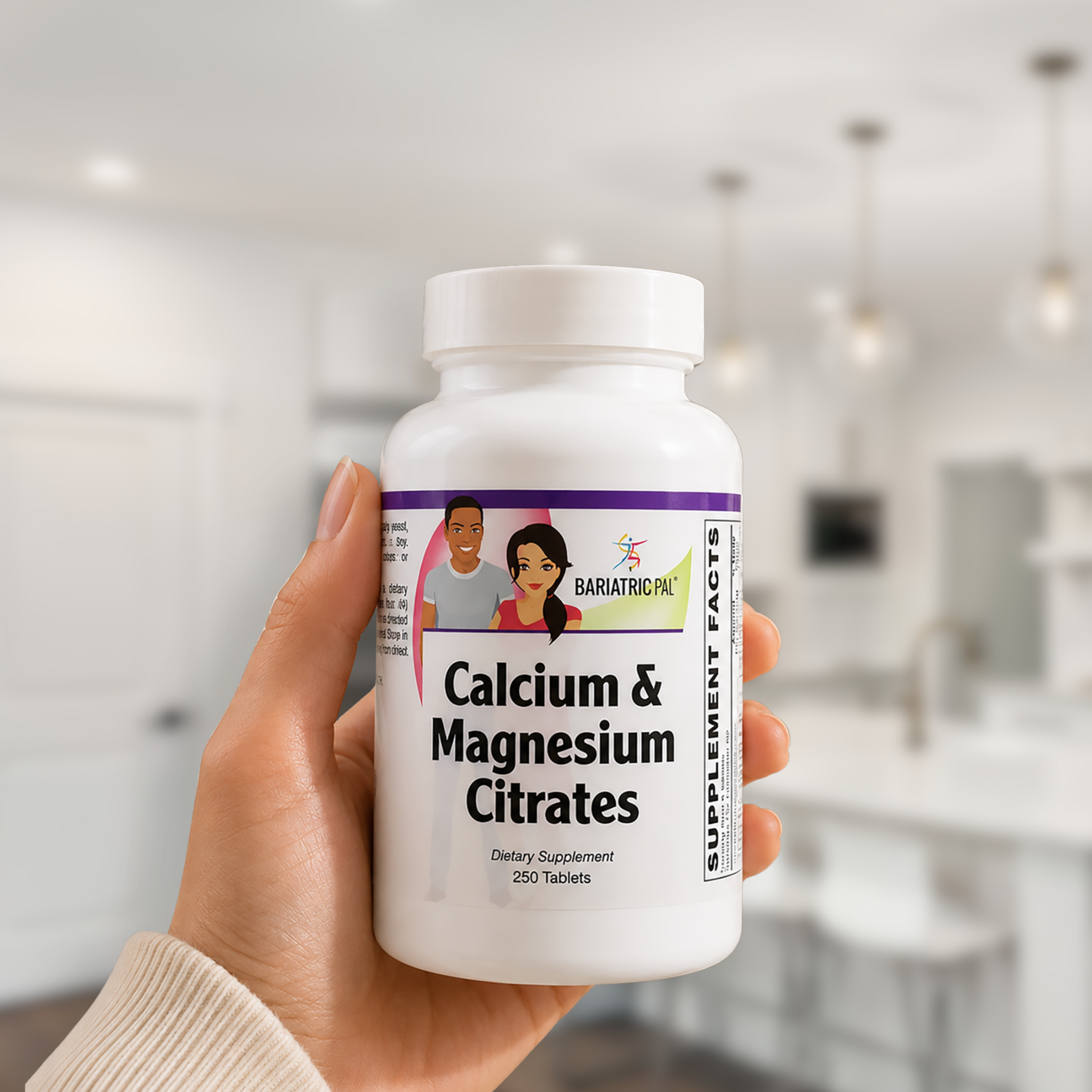 A hand holding a white bottle of BariatricPro Calcium & Magnesium Citrates dietary supplement, with a softly blurred modern kitchen in the background.