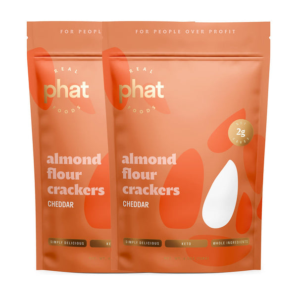 Two bags of Phat Foods almond flour crackers in cheddar flavor, featuring a warm orange design with white text highlighting "simply delicious," "keto," and "whole ingredients."