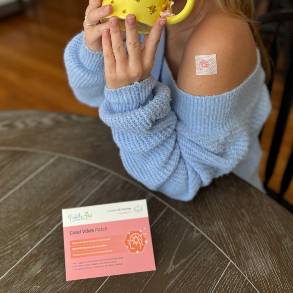 Person wearing a 'Good Vibes Patch' on their arm with a yellow mug, sitting on a wooden floor.