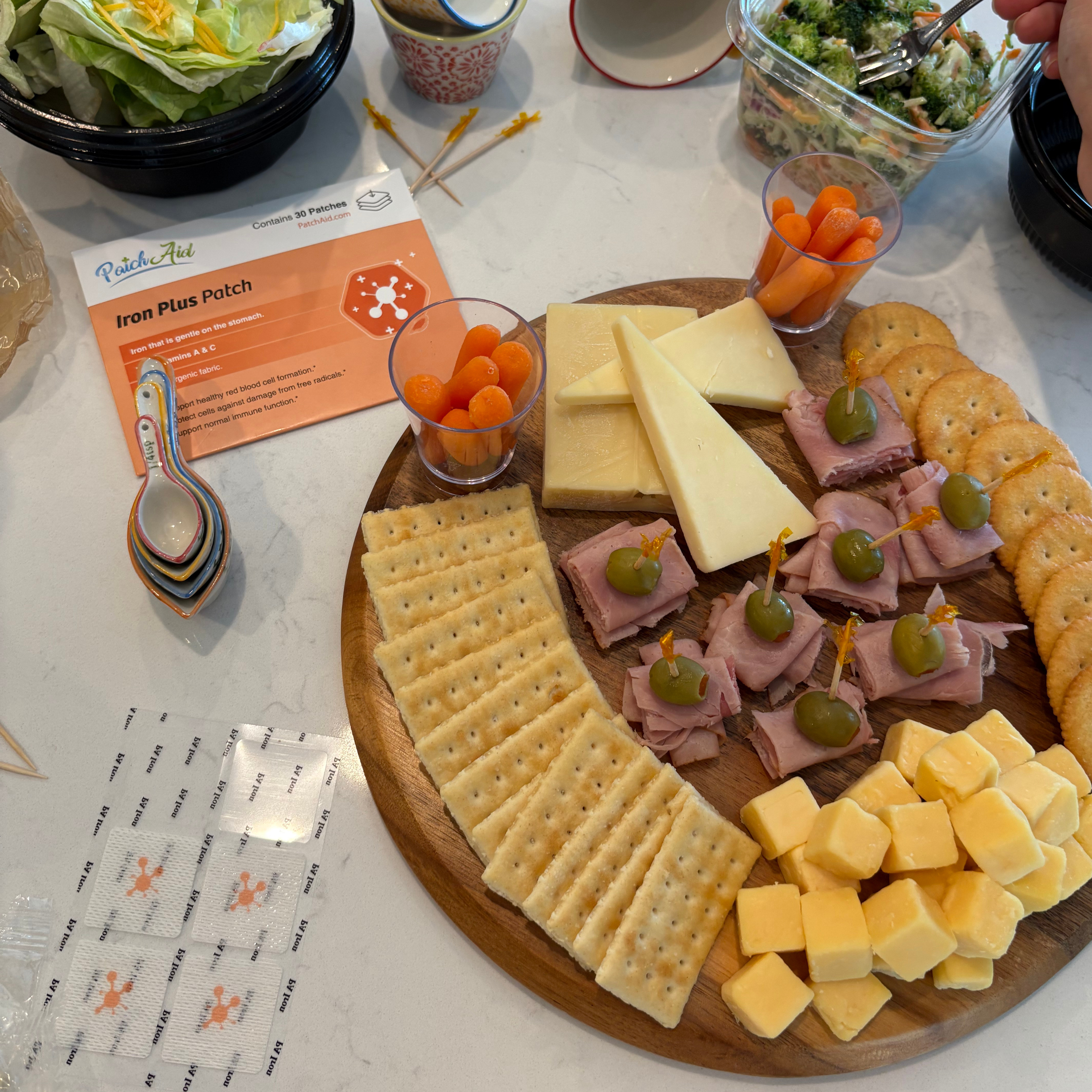 Platter of assorted cheeses, meats, and crackers on a table with a 'PediaSure' with Iron Plus Patch