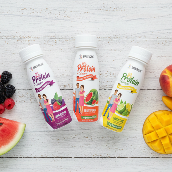 Three protein shot bottles labeled "Watermelon," "Fruit Punch," and "Lemon Lime" are arranged on a wooden surface, surrounded by fresh fruit like watermelon, mango, and berries.