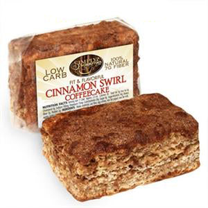 A package of low-carb cinnamon swirl coffeecake is displayed, showcasing a rectangular slice with a brown, cinnamon-sugar topping and a label highlighting its natural ingredients and fiber content.