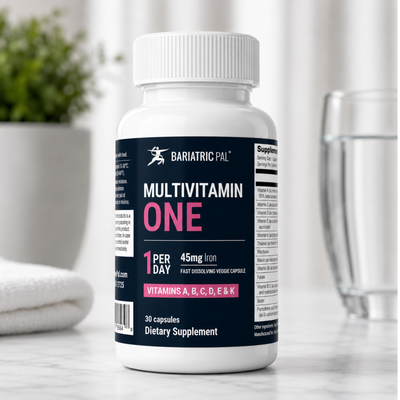 A white bottle of Bariatric Pal Multivitamin One, labeled with "1 Per Day" and "45mg Iron," sits on a marble surface next to a glass of water and a folded towel, indicating a dietary supplement for health.