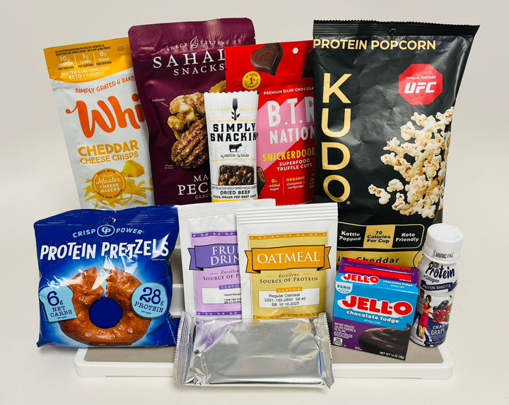 A variety of protein-rich snacks is displayed, including cheddar cheese crisps, protein popcorn, pretzels, oatmeal, and Jell-O, arranged on a white surface against a plain background.