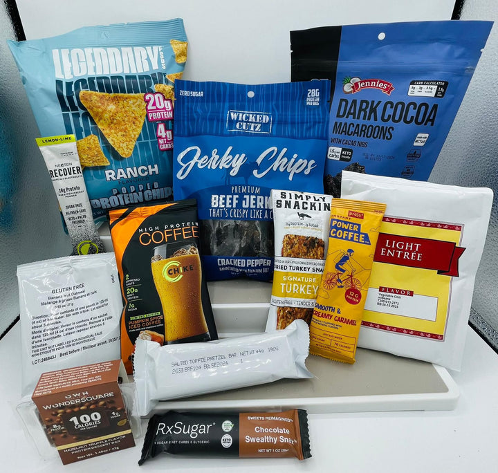 A variety of protein-rich snacks and beverages, including jerky chips, protein chips, coffee, and macaroons, are arranged on a white tray against a light background.