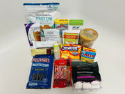 A variety of packaged food products, including protein snacks, sugar-free candy, soup, and marshmallows, are arranged on a white background for an e-commerce display.