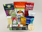 A variety of packaged snacks and food products, including rice, candy, protein shots, and oatmeal, are arranged on a white background, showcasing their colorful packaging and nutritional information.