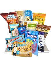 A variety of protein snacks and powders are displayed, including protein crisps, bars, and flavored powders, all arranged on a white surface for an appealing presentation.