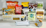 A variety of protein-rich food products, including protein powders, pasta, and snacks, are displayed on a white shelf, showcasing colorful packaging and nutritional information.