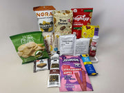 A variety of packaged snacks and food items, including seaweed snacks, crackers, soup, and candy, are arranged on a white surface, showcasing options for healthy eating and snacking.