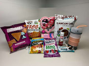 A variety of protein-rich snacks and products are arranged on a light background, including chips, pretzels, chili packets, and a water bottle, showcasing options for healthy eating.