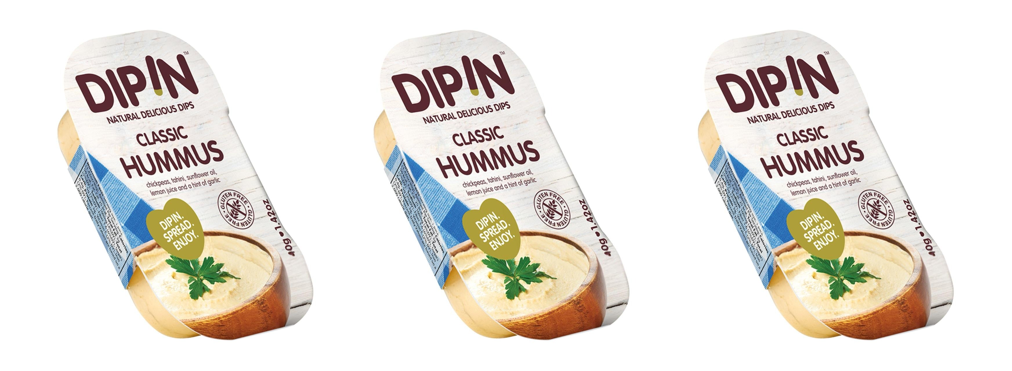 Three containers of DIP IN Classic Hummus are displayed, featuring a creamy texture topped with a sprig of parsley, with labels highlighting ingredients like chickpeas and tahini.