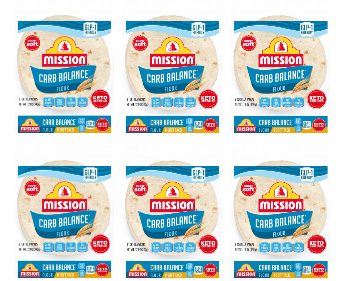 Six packages of Mission Carb Balance flour tortillas are displayed, each featuring a blue label indicating they are keto-friendly, with details about net carbs and serving size prominently shown.