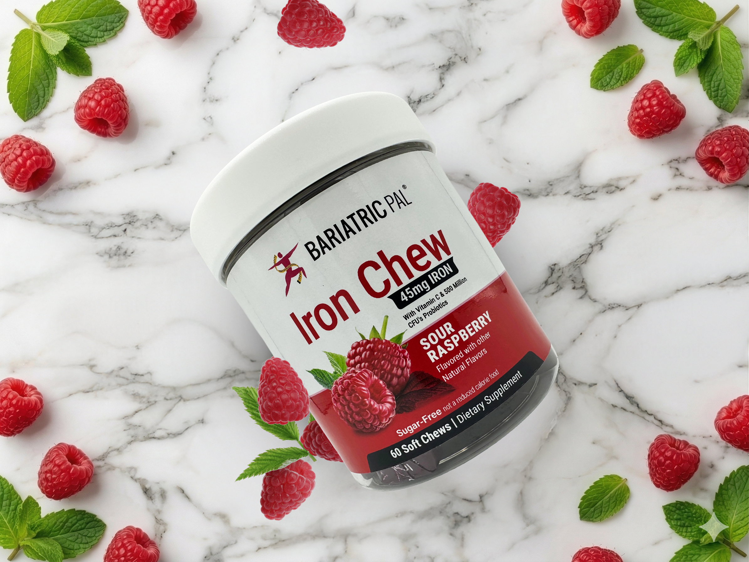 A container of Bariatric Pal Iron Chew in Sour Raspberry flavor sits on a marble surface, surrounded by fresh raspberries and mint leaves, highlighting its dietary supplement features.