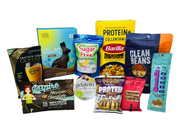 A variety of protein-rich snacks and products are displayed, including chocolate bunnies, protein coffee, and pasta, showcasing colorful packaging and diverse flavors.