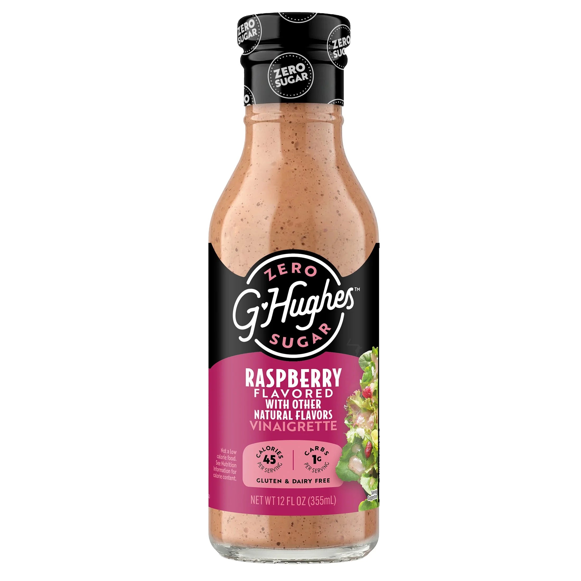 A clear glass bottle of G. Hughes Zero Sugar Raspberry Vinaigrette, featuring a black cap and a pink label, showcases the product's flavor and nutritional information prominently.