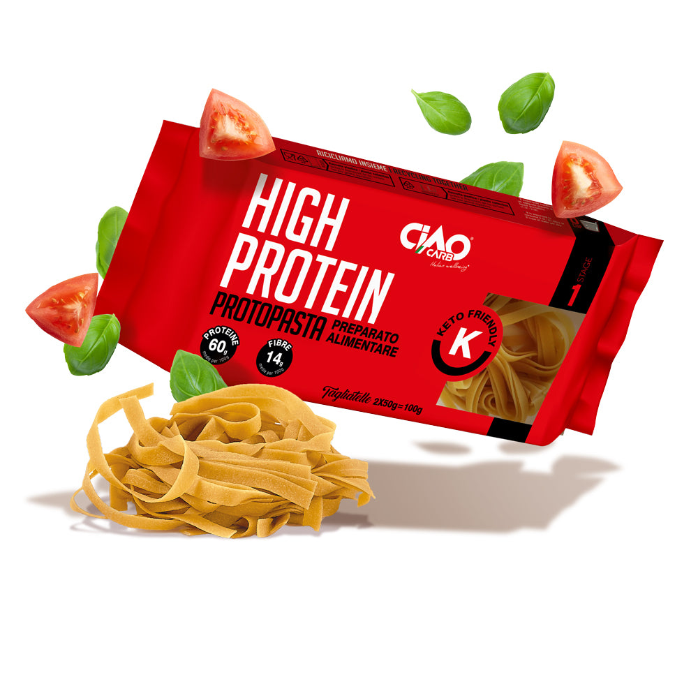 A package of high protein pasta labeled "Ciao Carb" is surrounded by fresh basil leaves and sliced tomatoes, with a portion of pasta laid out in front, emphasizing its keto-friendly attributes.