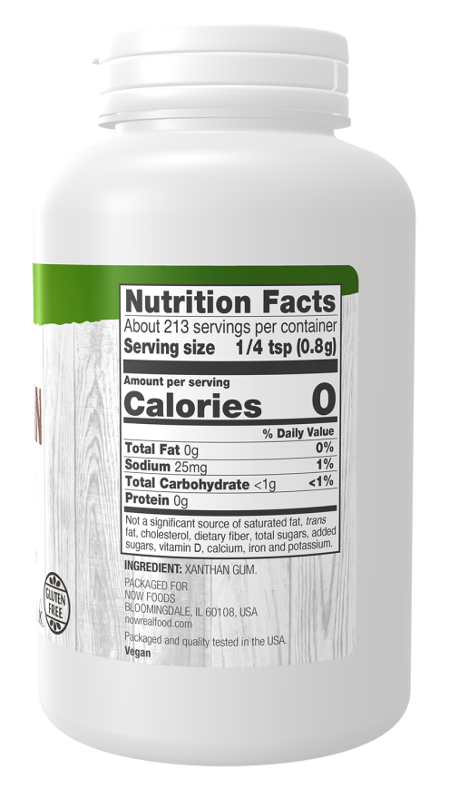 A white plastic container labeled "Nutrition Facts" displays serving details and ingredients, highlighting zero calories and containing xanthan gum, set against a light wood background.